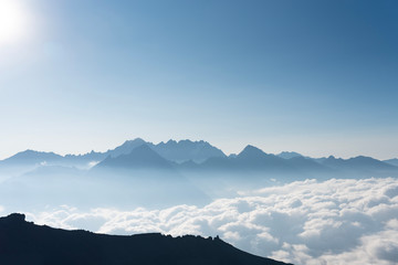 Caucasus mountains top peeks above the clouds, illuminated by the sun after sunrise. Awesome view from Kazbek mountain, Georgia. Travel motivation concept. Copy space, moc up.