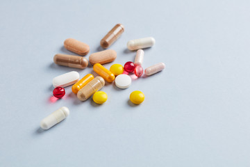 Multicolor vitamins and supplements on bright paper background. Concept for a healthy dietary supplementation. Copy space. 