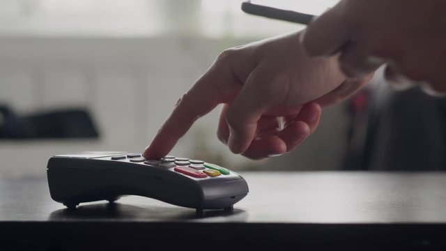 Close-up customer uses smartphone to make a wireless payment with password