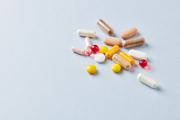 Multicolor vitamins and supplements on bright paper background. Concept for a healthy dietary supplementation. Copy space. 