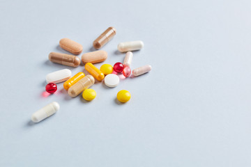 Multicolor vitamins and supplements on bright paper background. Concept for a healthy dietary supplementation. Copy space. 