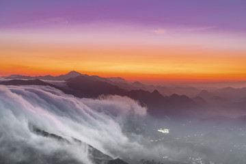 clouds flowing down the mountains like a river at sunset