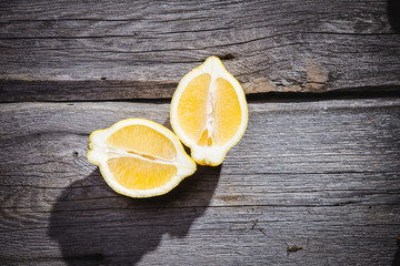 Photo of fresh ripe lemons on retro background. A slice of lemon with green leaves. Lemon fruit on wooden plate bowl. Lemon around fruits. Copy space. Grey background. Image