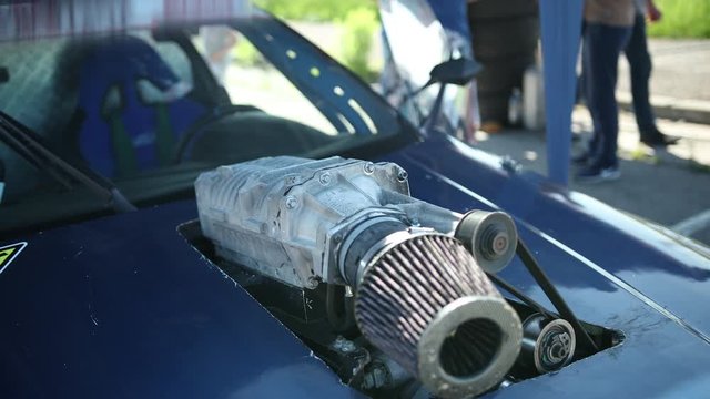 blue sports car for street drift racing, with a cut in the hood and a zero resistance filter from the top, outside on a Sunny day, close-up, slow motion