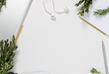 Workspace with tablet, pencil, green branches on white background. top view