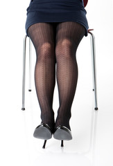 An image of a woman legs sitting on a chair.