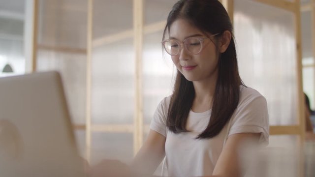 Freelance Asian women working on laptop at office. Young Asia business Girl using the computer for trade, send email, digital work on the internet on table at workplace concept. Slow motion.