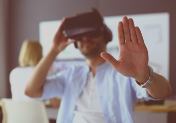 Young male software programmer testing a new app with 3d virtual reality glasses in office.