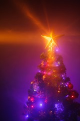 Fototapeta na wymiar Christmas tree with festive lights, purple background with mist