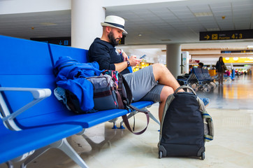 Young man with hat waiting with his luggage in an airport