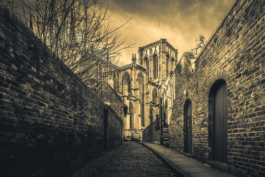 YORK, ENGLAND, DECEMBER 13, 2018: cobbled brick street that leads to the magnificent York Minster Cathedral, with narrow red brick walls at both sides.