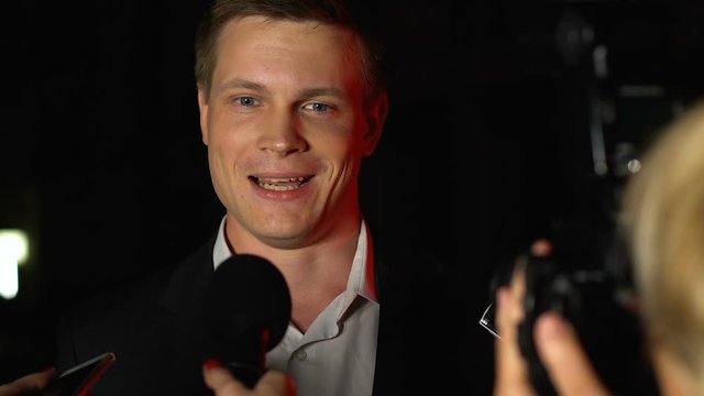 Male politician giving exclusive interview to media front camera flashes, news
