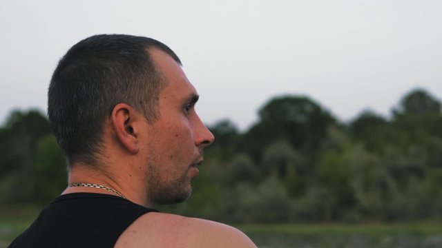 Close-Up Religious Man Attentively Repeats Mantra Sitting On Lake Shore