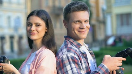 Young smiling man and woman holding cameras, creative profession, photographers