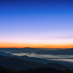 Beautiful foggy winter sunrise in mountains background.