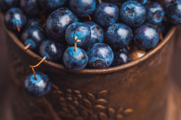 Freshly harvested blueberries in metal cup. Selective focus. Shallow depth of field.