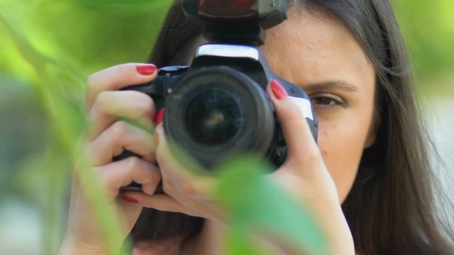Female detective taking photo by camera hiding park, journalist spying celebrity