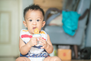 Infant toddler baby boy trying eat orange fruit