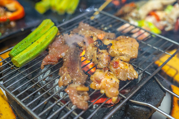 Grilling marinated meat and lady finger vegetables on charcoal stove