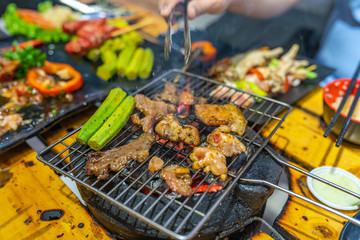 Grilling marinated meat and okra vegetables on charcoal stove