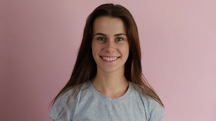 Close up of a happy young female with long hair lifting her head isolated over a pink background. People sincere emotions lifestyle.