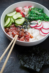 Poke with tuna served in a white bowl, vertical shot, selective focus, closeup