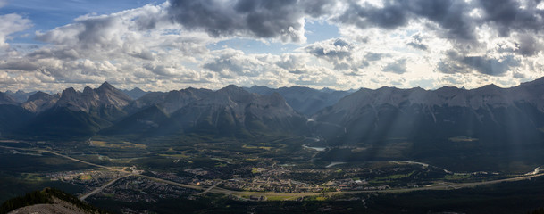 Fototapeta na wymiar Beautiful Panoramic View of a small city in the Canadian Rocky Mountain Landscape during a cloudy and rainy day. Taken from Mt Lady MacDonald, Canmore, Alberta, Canada.