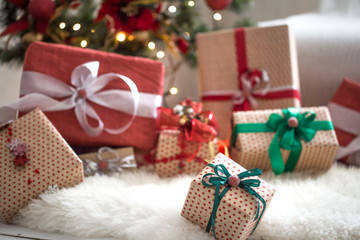 Christmas presents over Christmas lights and Christmas tree on light background on cozy rug. Christmas decorations