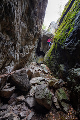 Fototapeta na wymiar Adventurous girl is climbing down into a rocky cave. Taken in Skaha Bluffs Provincial Park, Penticton, British Columbia, Canada.