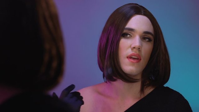 Transvestite spraying perfume and smiling mirror reflection, gender identity