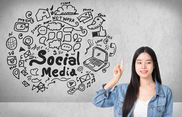Asian young woman looking up of Hand drawn illustration of social media sign and symbol doodles icon.Concrete wall with a social media sketch.