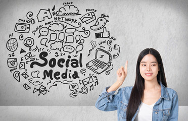 Fototapeta premium Asian young woman looking up of Hand drawn illustration of social media sign and symbol doodles icon.Concrete wall with a social media sketch.