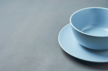 Group of modern empty ceramic plates of blue color lies on dark concrete background. Top view