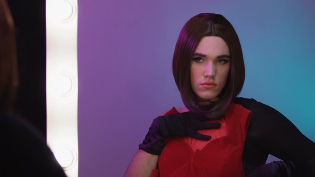 Transgender wearing wig trying on female dresses, travesti show, cross-dressing