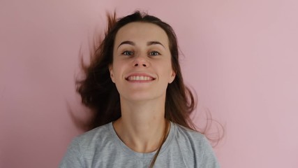 Pleased and joyful European young woman with long hair lifting her head, smiles positively, isolated over a pink background. People sincere emotions lifestyle.