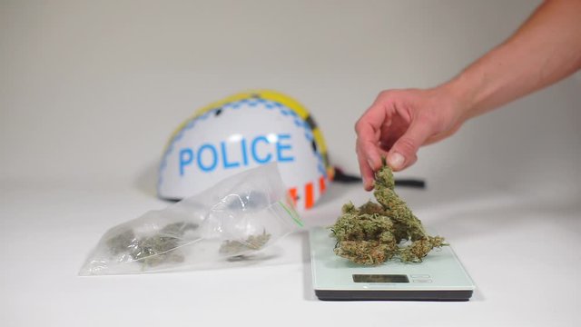 hand puts cannabis on the scales opposite the inscription police