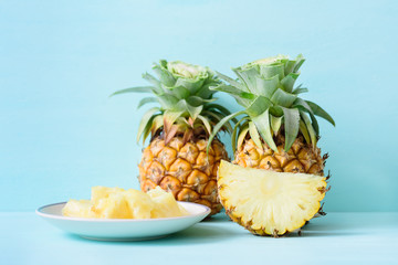 Sliced pineapple on white dish and pineapple fruit on pastel background