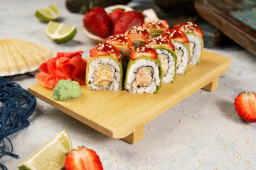 Japanese rolls with strawberries and avocado on a wooden stand