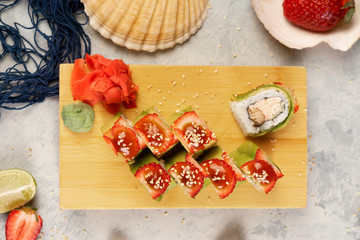 Japanese rolls with strawberries and avocado on a wooden stand