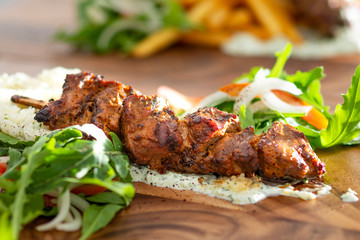 Close up of chicken kebab on rice with salad.