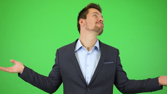 A young handsome businessman smiles at the camera and throws out his hands, unable to choose from large selection - green screen studio