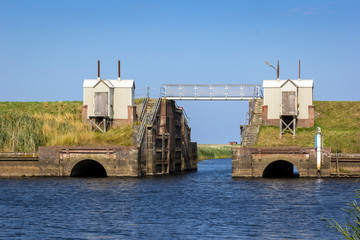 View of a small and old lock on a river flowing into the North Sea