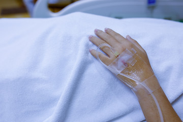 hand of a patient with medical drip or IV drip in hospital,Patient with drip receiving a saline solution.patient lying on bed in hospital