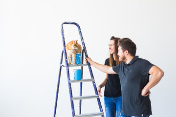 Teamwork and repair concept - young couple with cat doing a renovation in new apartment