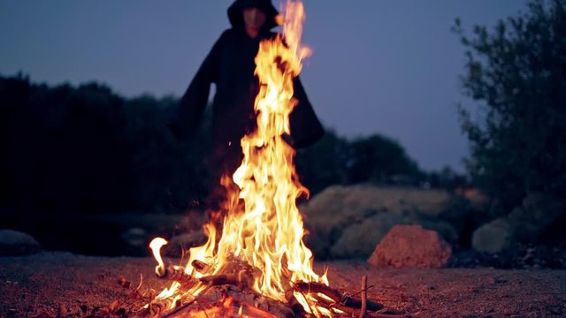The old witch cooks a sorcery potion in the thicket of the forest. Fairy tales on Halloween. Burning fire.