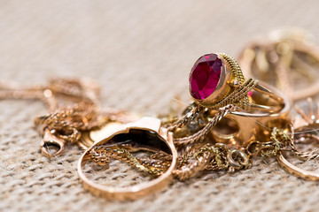 Real gold rings with diamonds, gemstones, earrings and necklaces on rough hemp material close up macro .