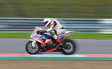 Obraz na płótnie Canvas Motorcycle rider racing at high speed on race track