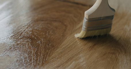 applying oil finish to oak surface with brush