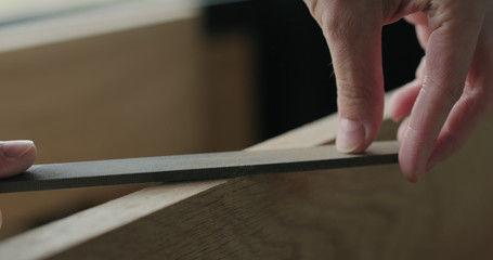 closeup man hand sandig oak board edge with file