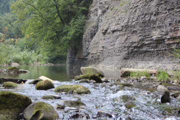 fast water of a mountain stream falls by a stormy waterfall among the rocks